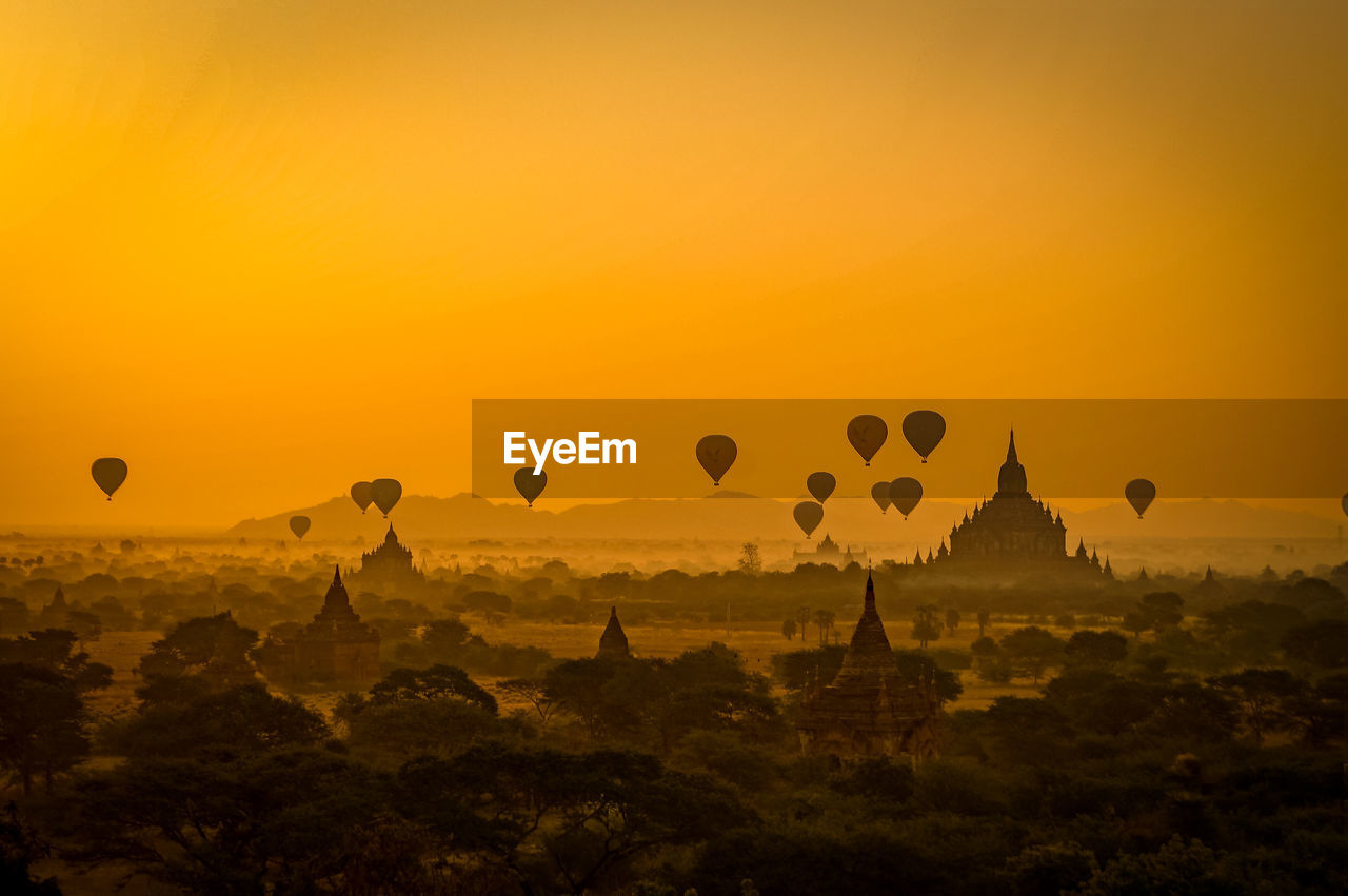 Hot air balloons flying against sky during sunset