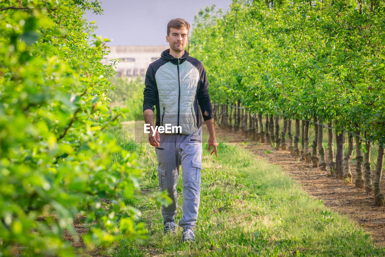 FULL LENGTH PORTRAIT OF YOUNG MAN STANDING ON FARM