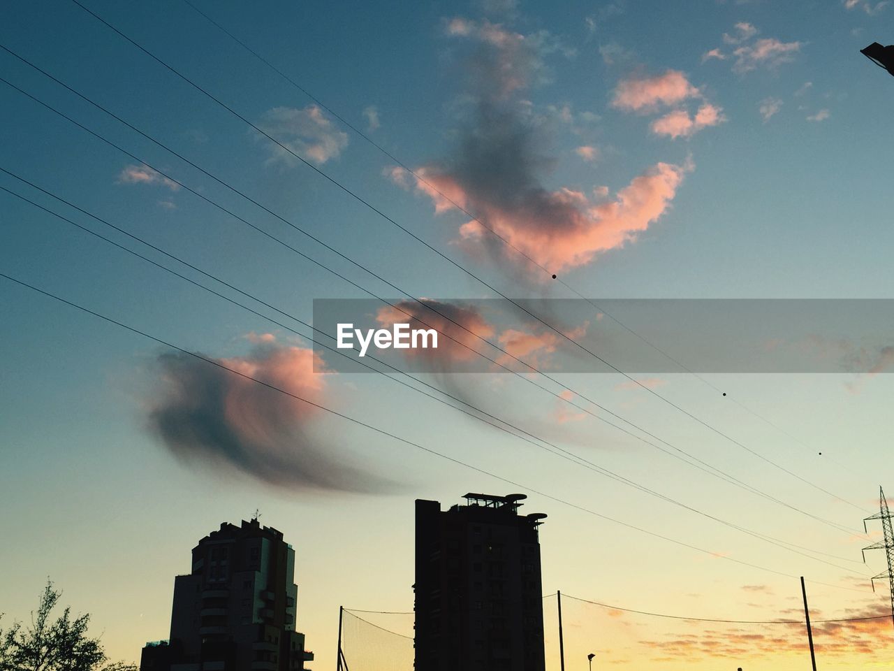 Low angle view of silhouette buildings against cloudy sky at sunset