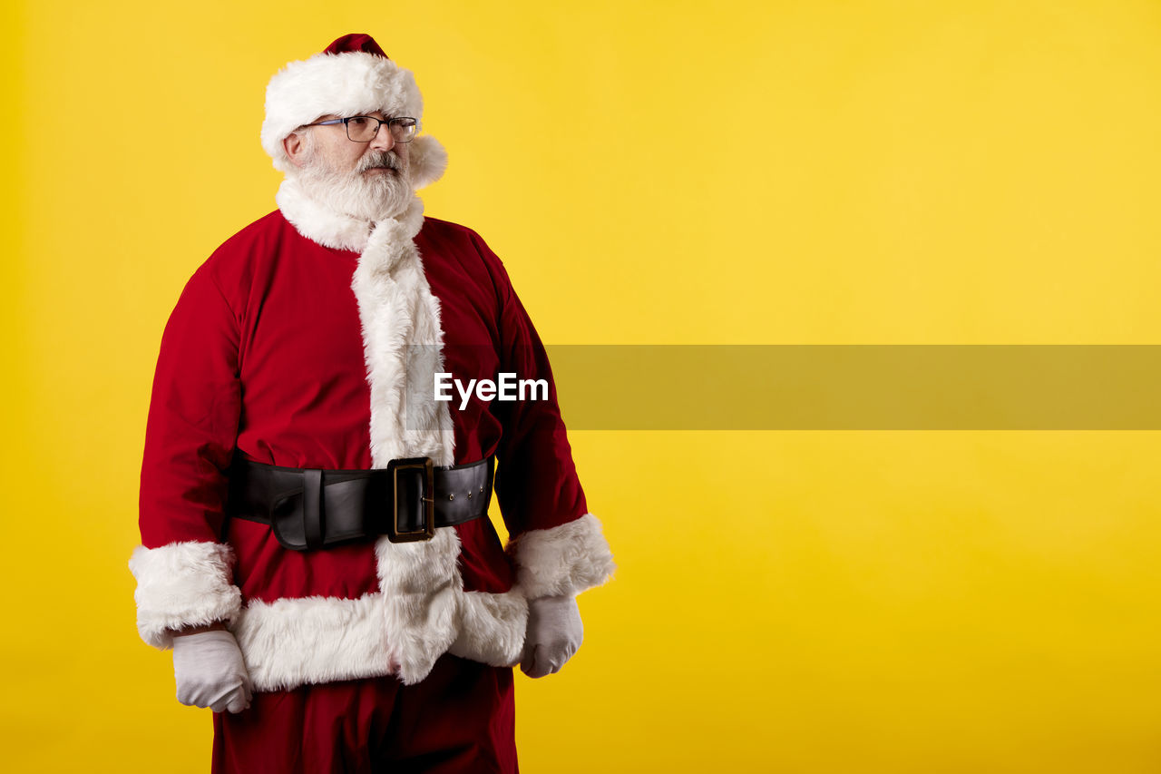Santa claus pointing his eyes at a poster on a yellow background