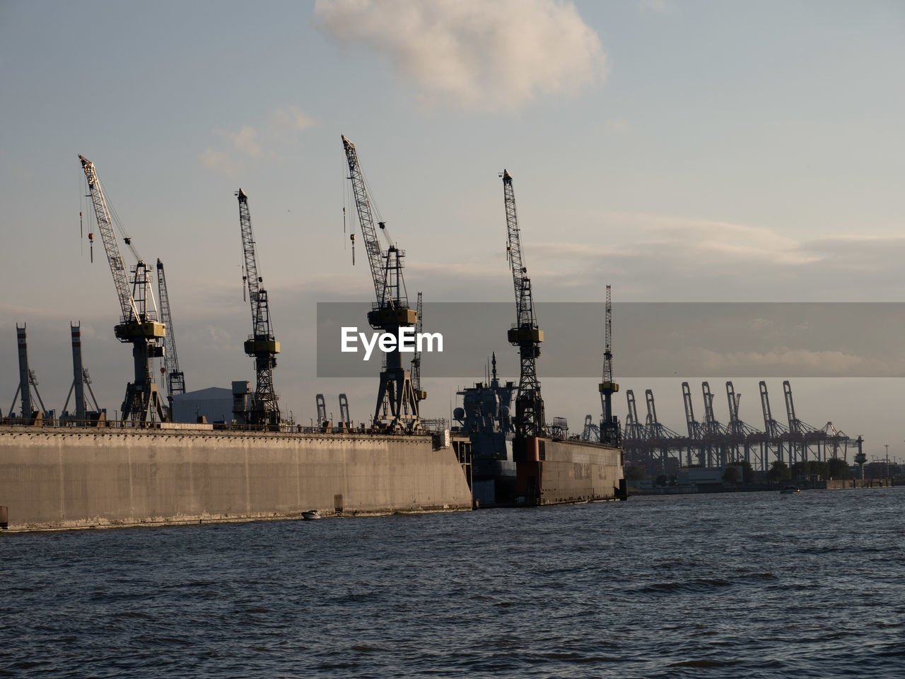 Cranes at commercial dock against sky