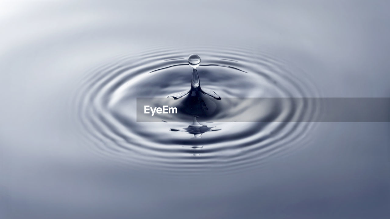 HIGH ANGLE VIEW OF DROP FALLING ON WATER IN LAKE