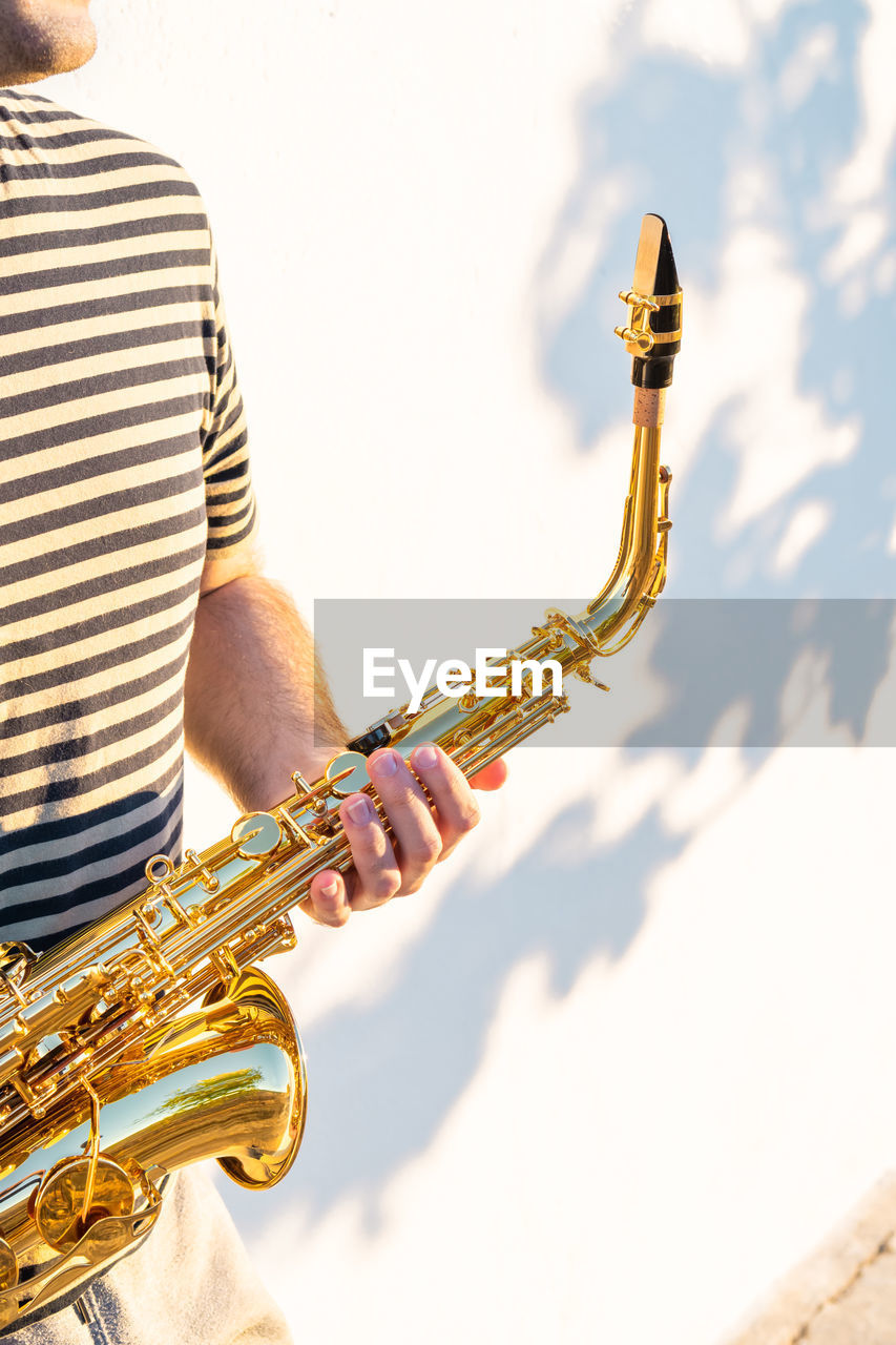 Midsection of man holding saxophone