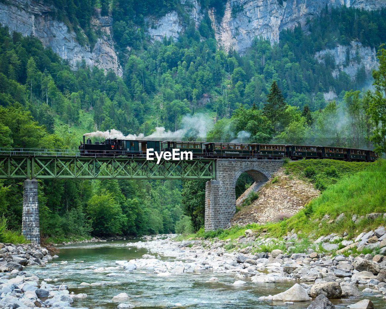 Train on railway bridge against mountain