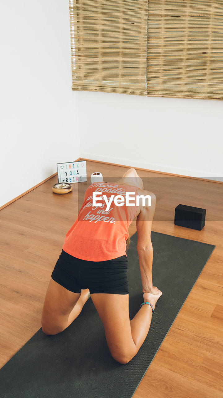 side view of young woman exercising on floor at home