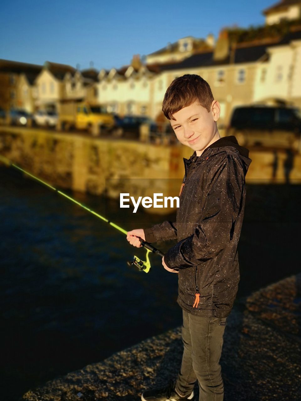 Portrait of boy holding fishing rod by lake