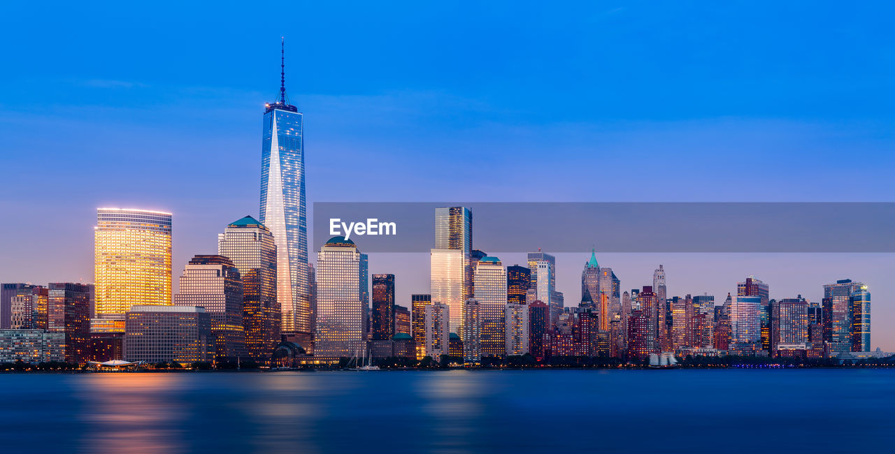 Illuminated lower manhattan buildings by hudson river