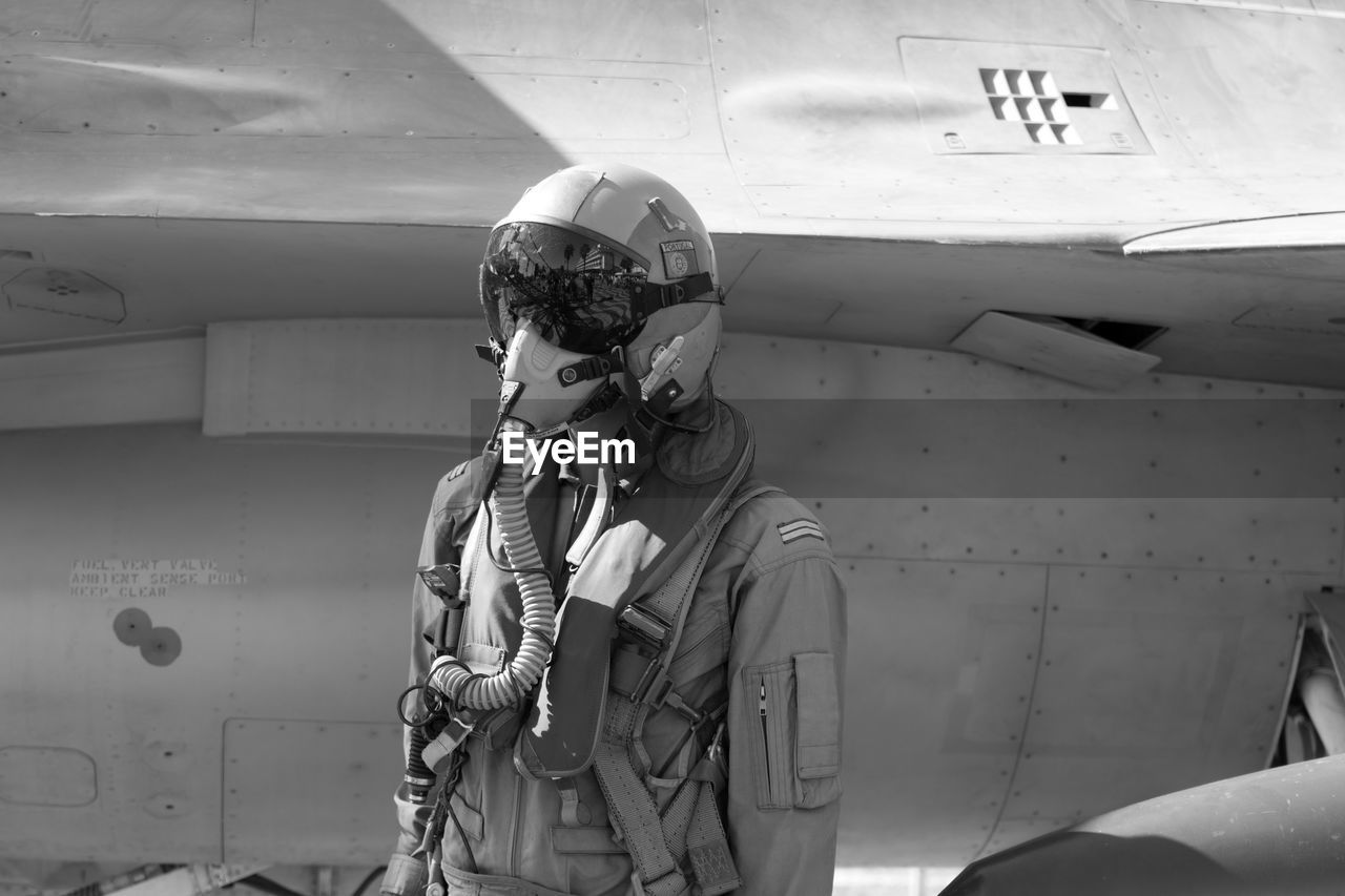 Pilot standing against airplane