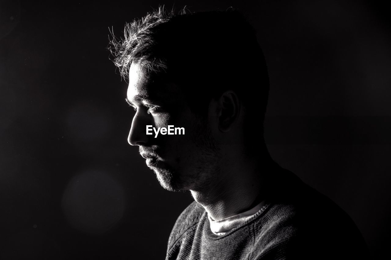 Profile view of man with stubble over black background