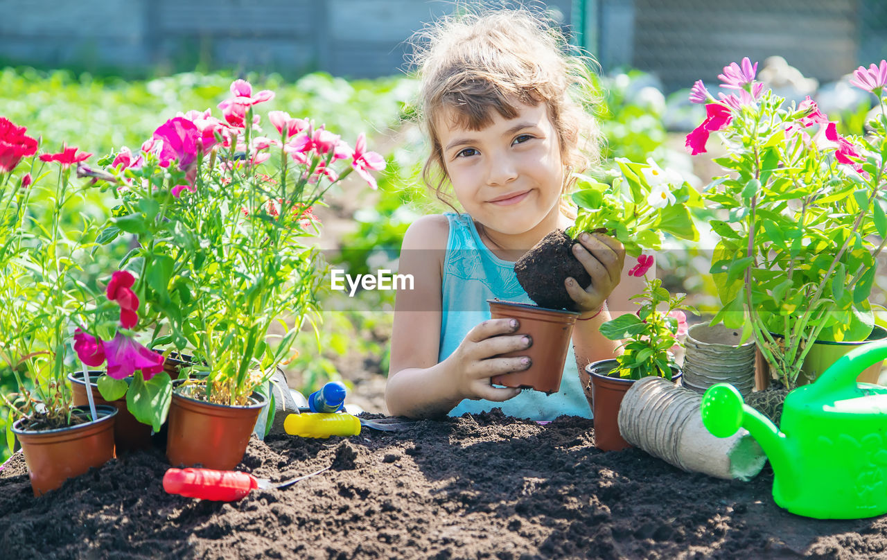 portrait of smiling young woman picking flowers on field