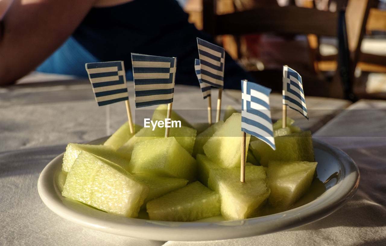 Small greek flags stuck in fruit slices on plate