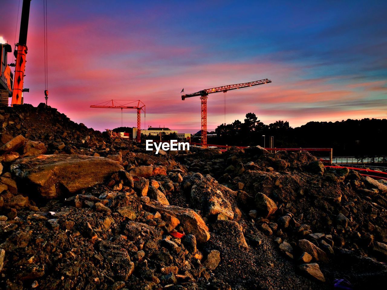 CRANES AT CONSTRUCTION SITE DURING SUNSET