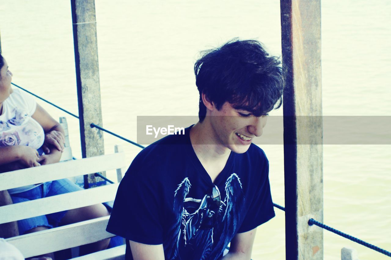 Young man smiling while sitting in ferry boat