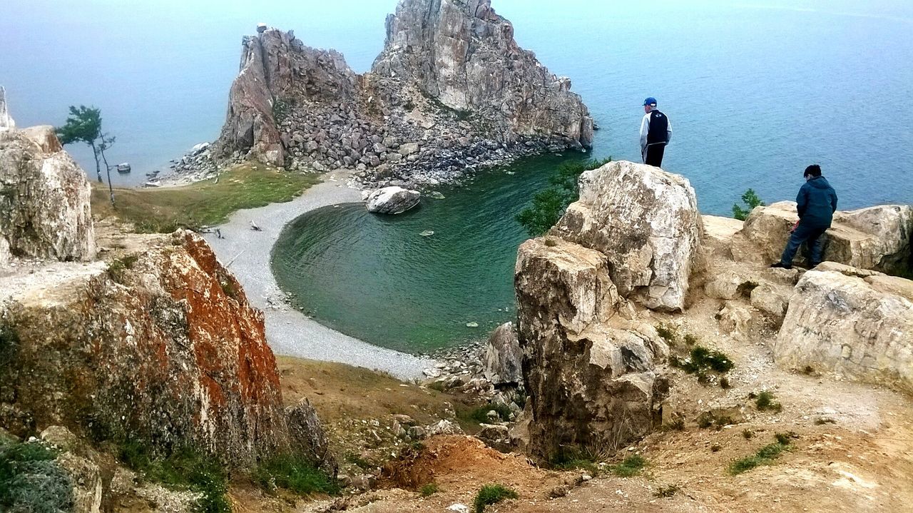 People standing on cliff against sea