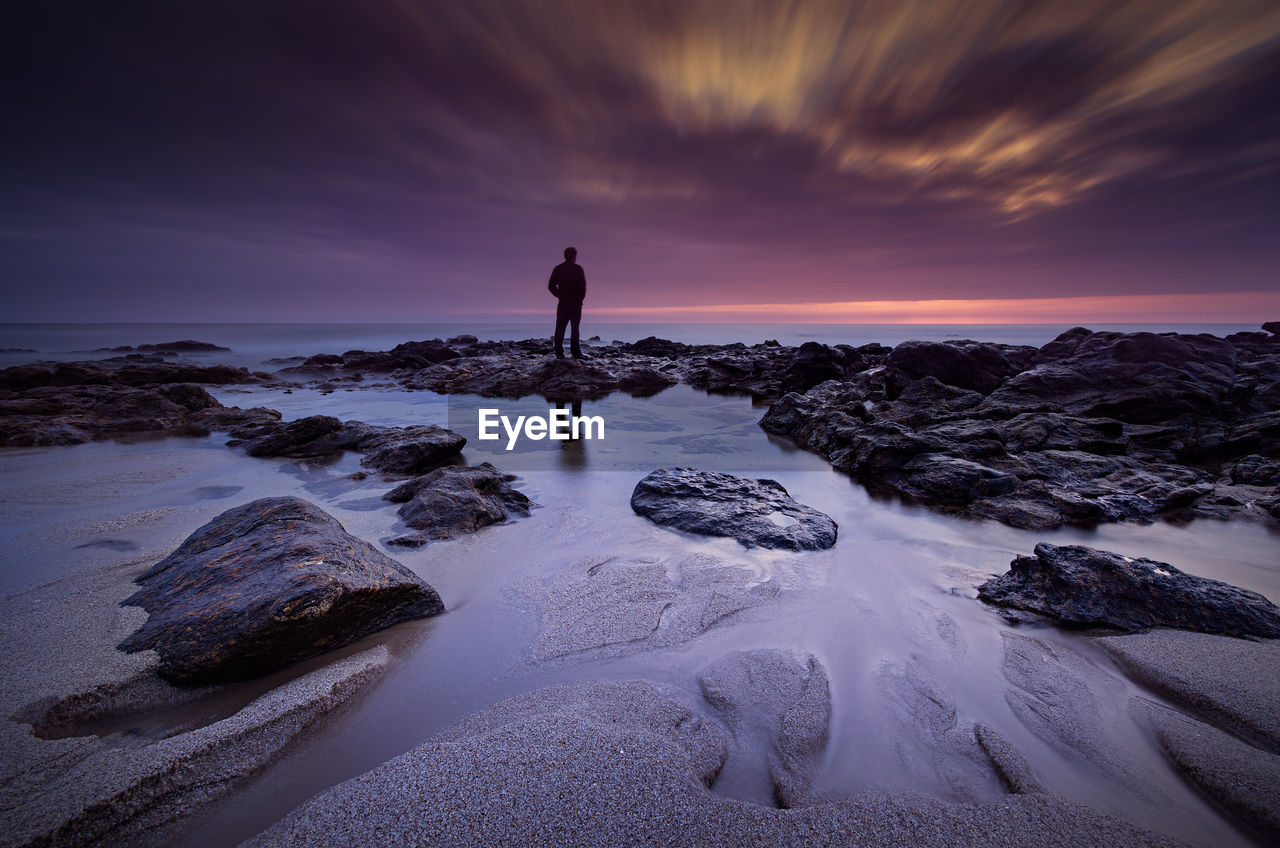 Silhouette man standing on beach against sky during sunset