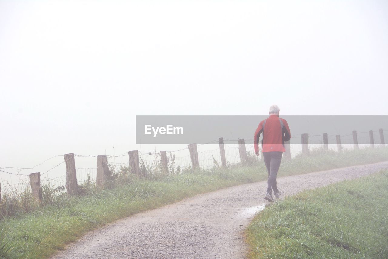 Rear view of man walking in foggy weather