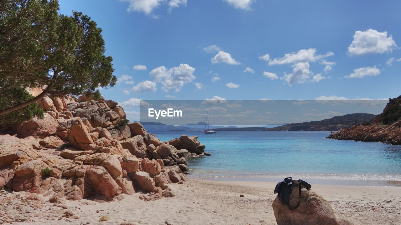 Rock formations at seashore against sky