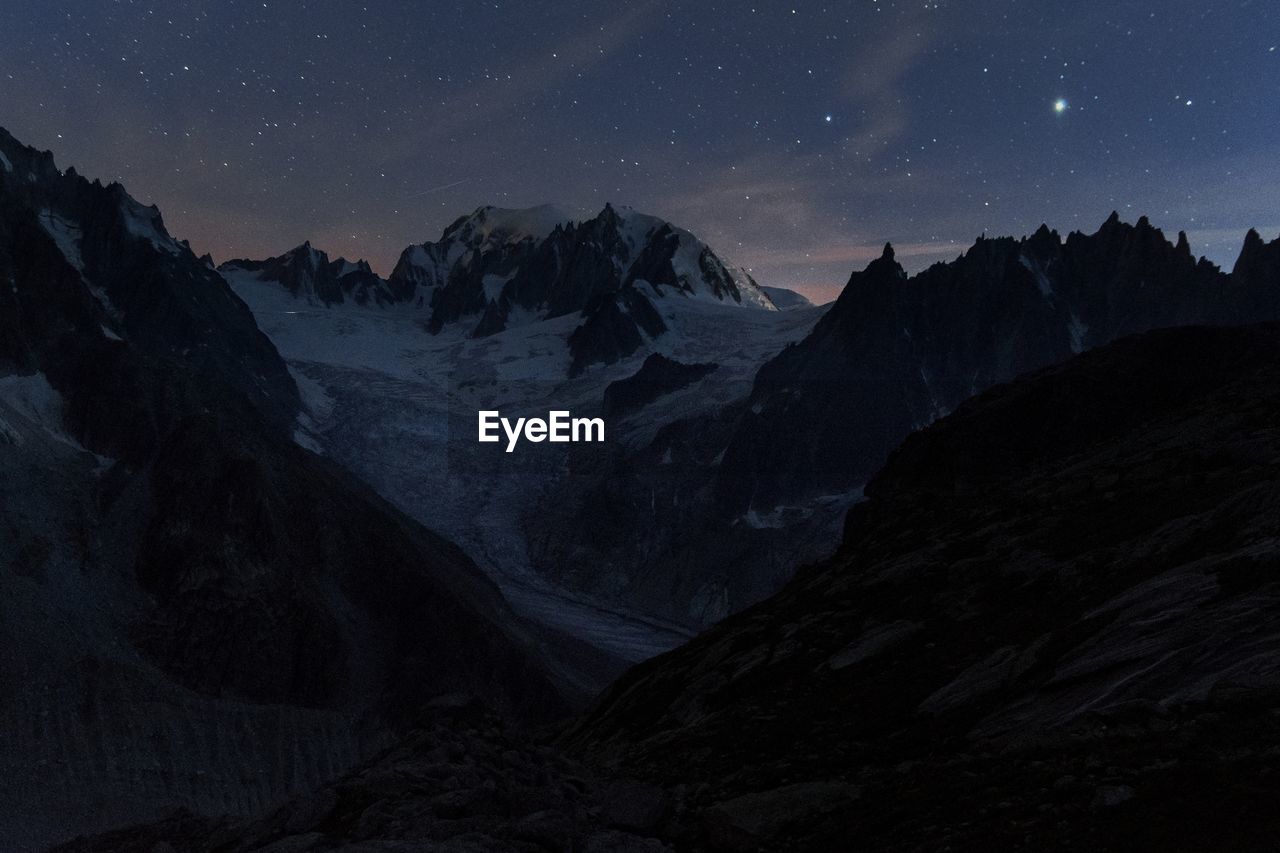 Scenic view of snowcapped mountains against sky at night