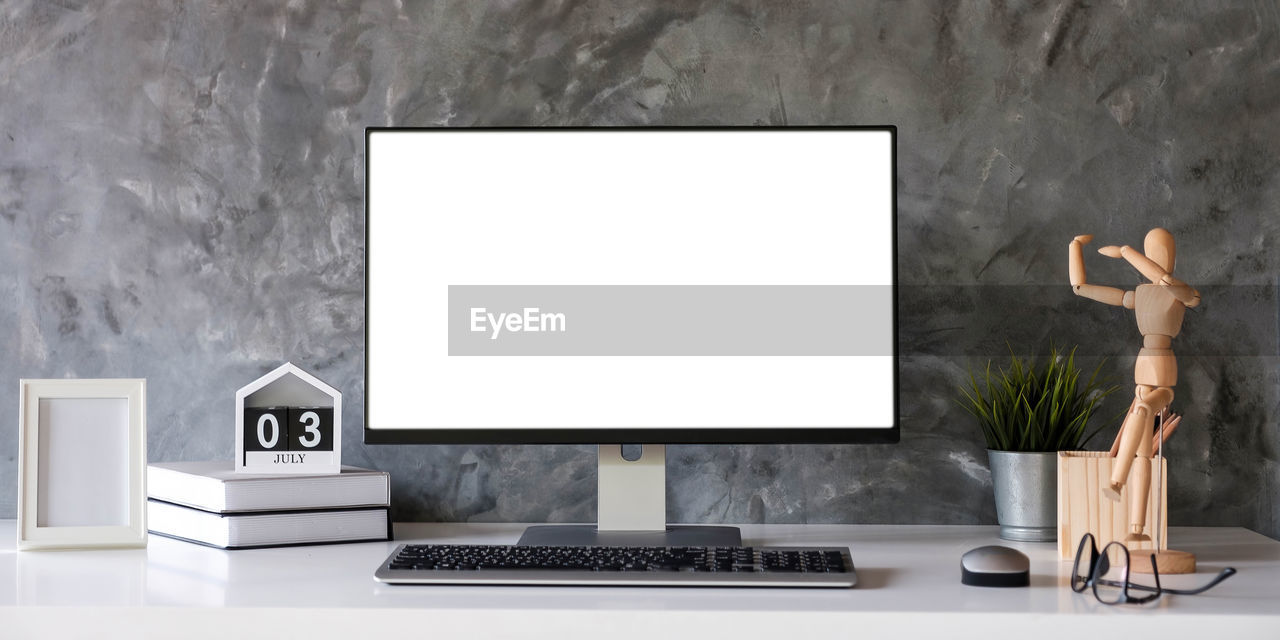 Blank screen desktop computer in minimal office room with decorations and copy space