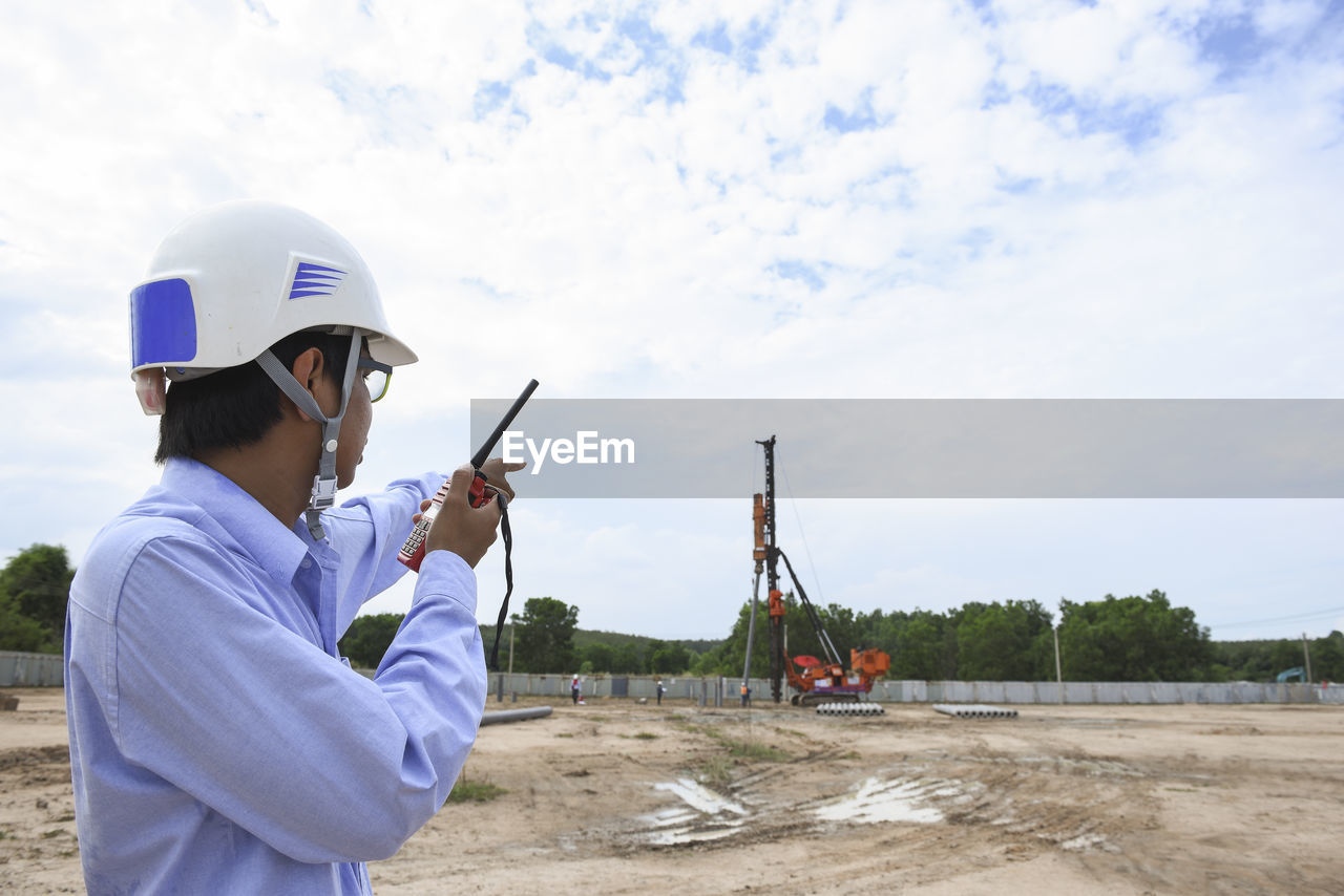 Side view of businessman talking over walkie-talkie at construction site