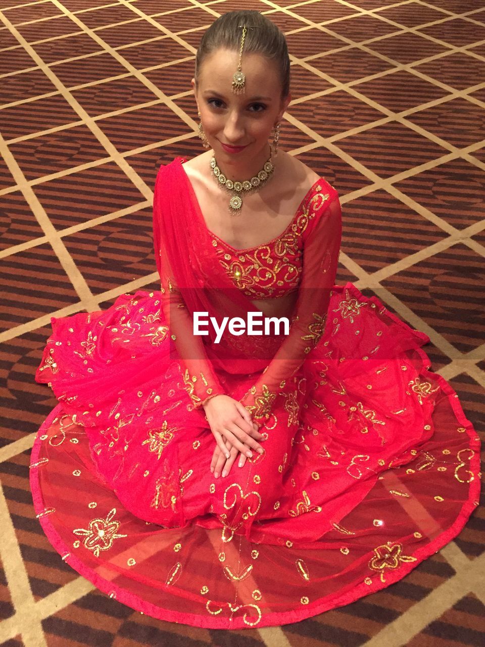 Portrait of smiling young woman in traditional clothing sitting on floor