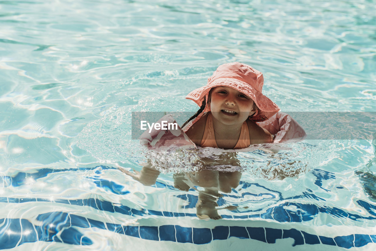 Young preschool age girl swimming in pool on vacation in palm springs