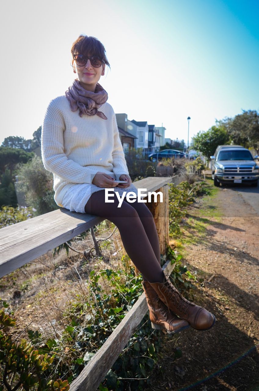 Young woman sitting on edge of a wooden bench