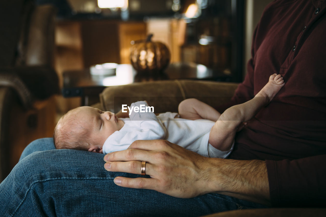 Cute daughter lying on father's laps at home