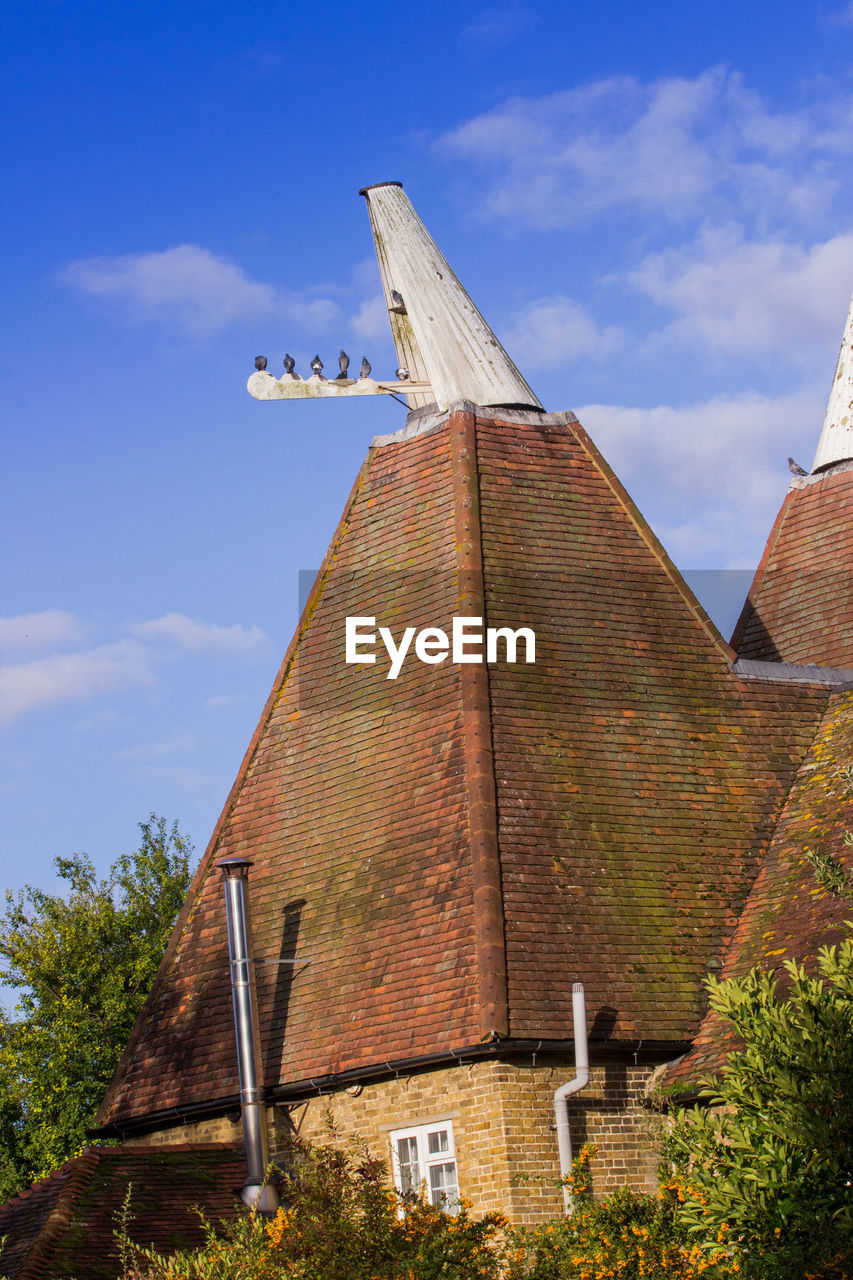 LOW ANGLE VIEW OF TRADITIONAL BUILDING BY TREES AGAINST SKY