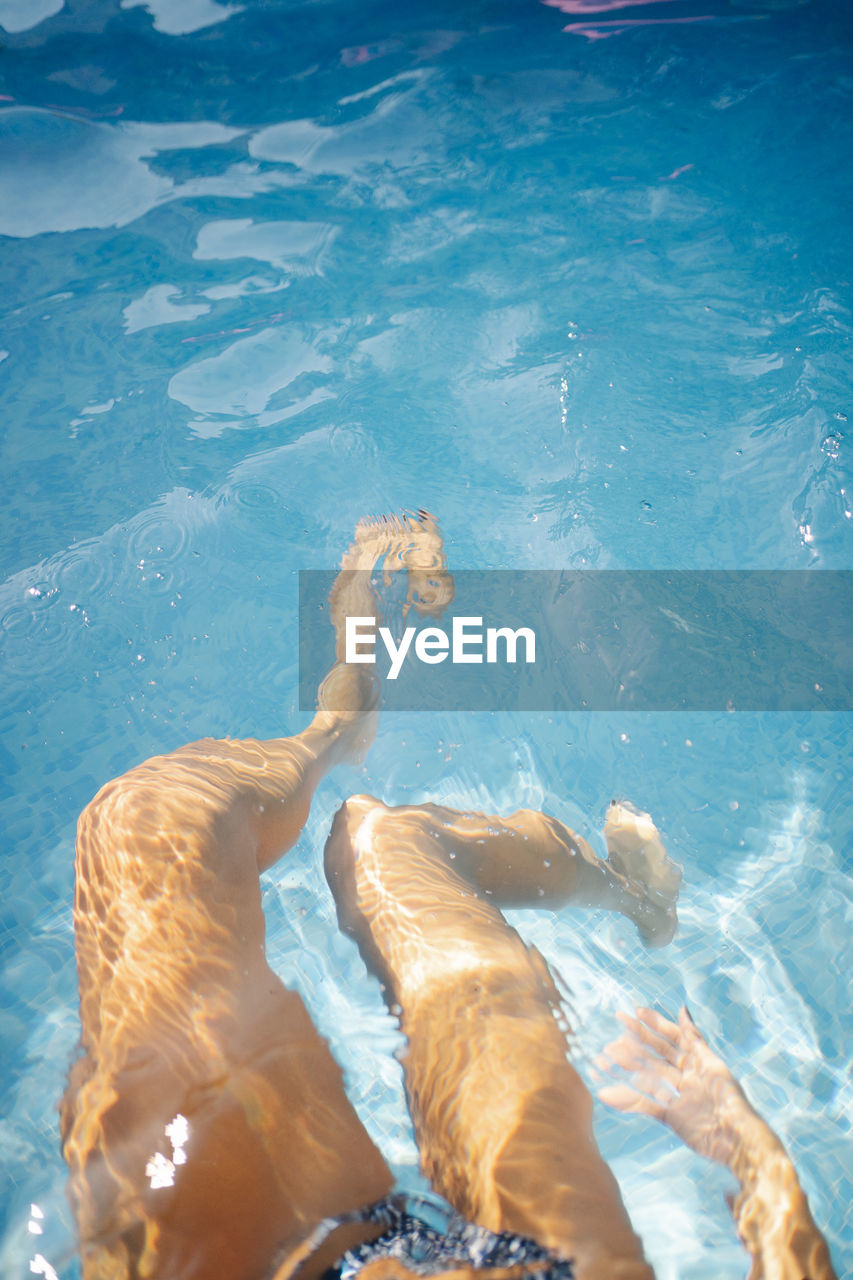 HIGH ANGLE VIEW OF MAN SWIMMING IN POOL