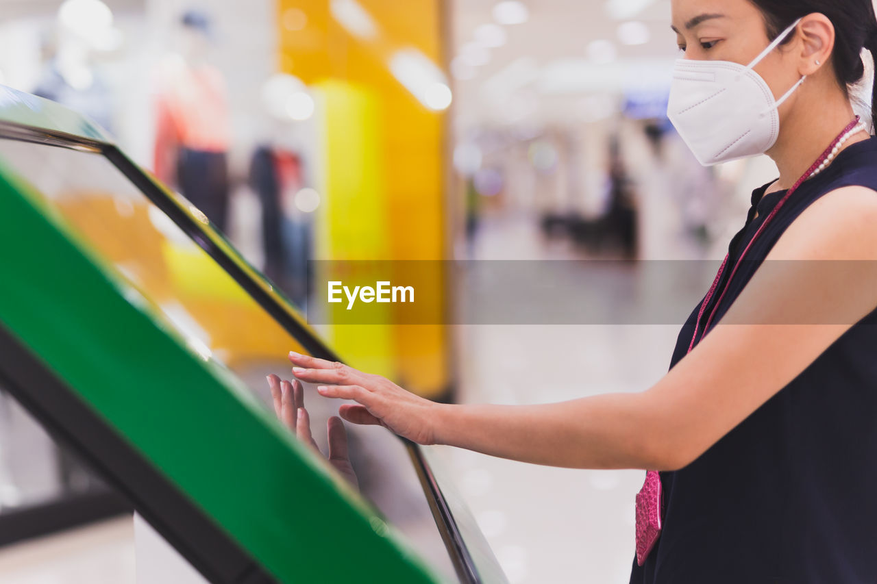 Woman in protective mask hand uses digital touch screen to get information.