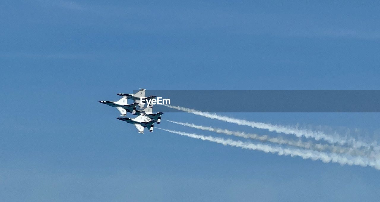 low angle view of airplane flying against clear blue sky