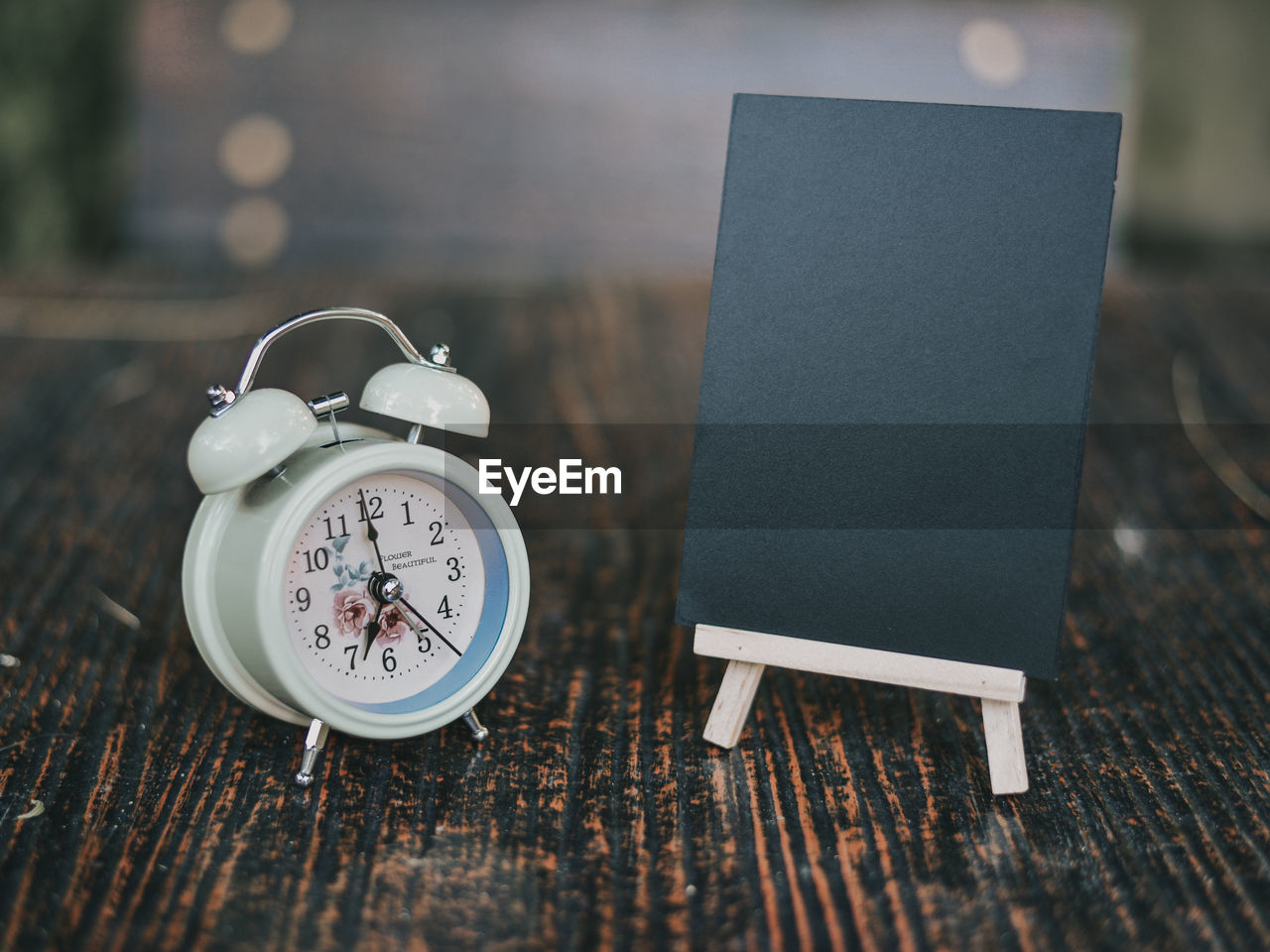 Close-up of clock and blank blackboard on table