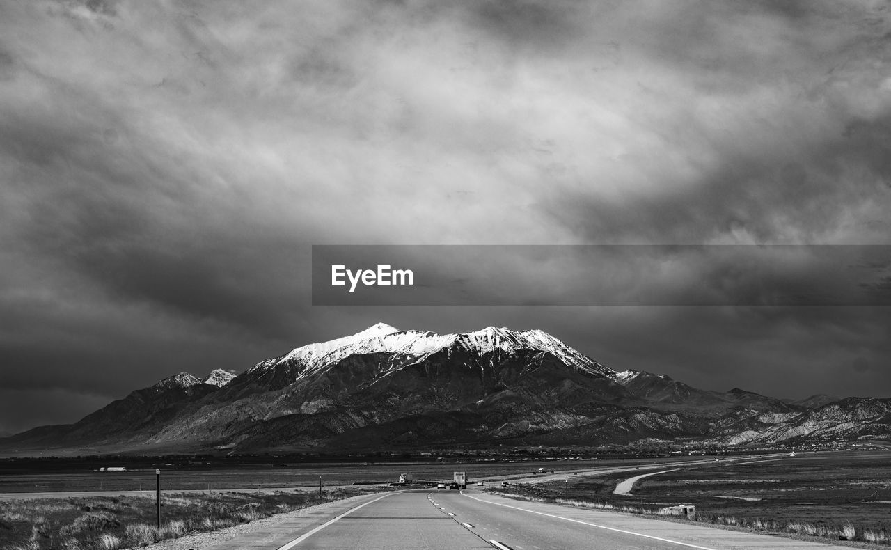 Road leading towards snowcapped mountains against sky