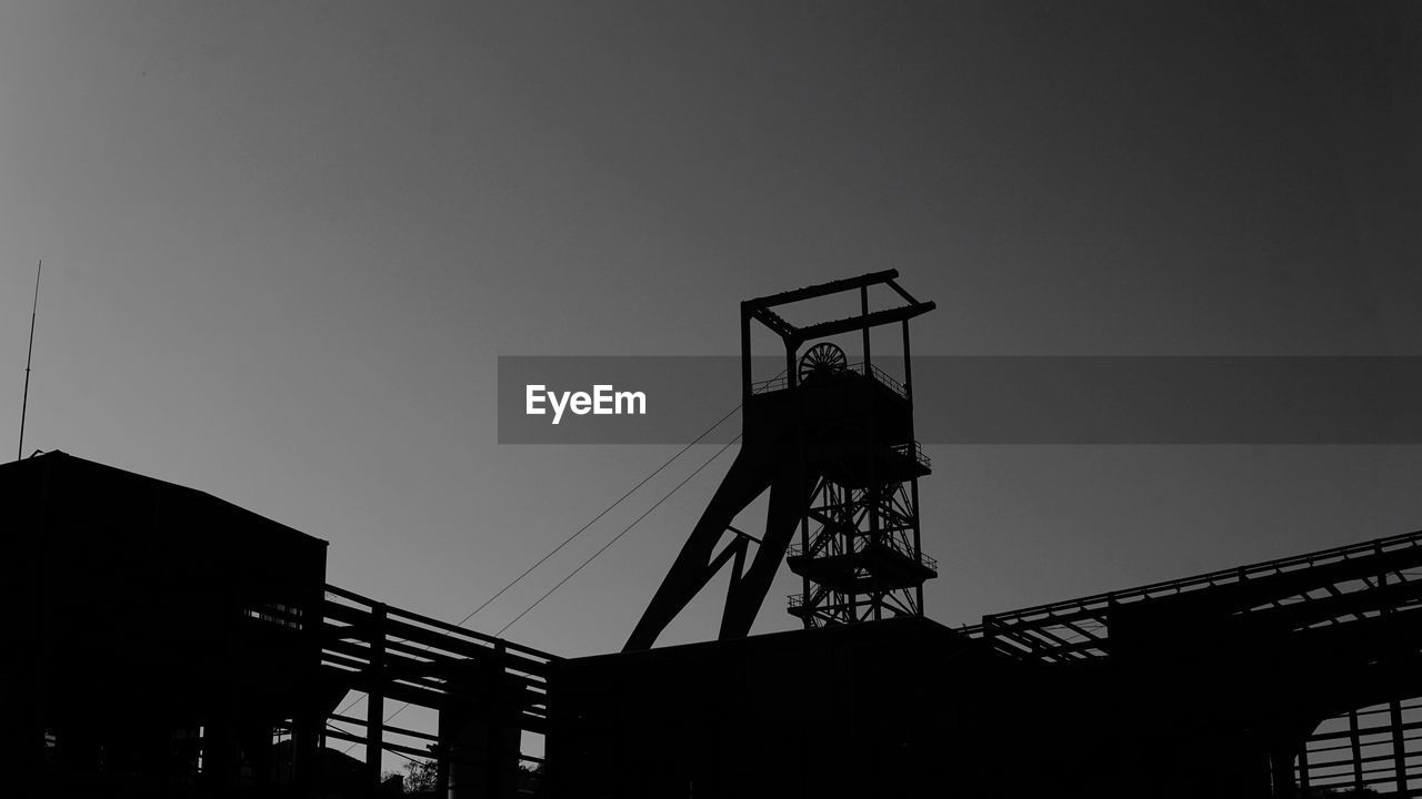 LOW ANGLE VIEW OF SILHOUETTE CRANE AGAINST CLEAR SKY AT SUNSET
