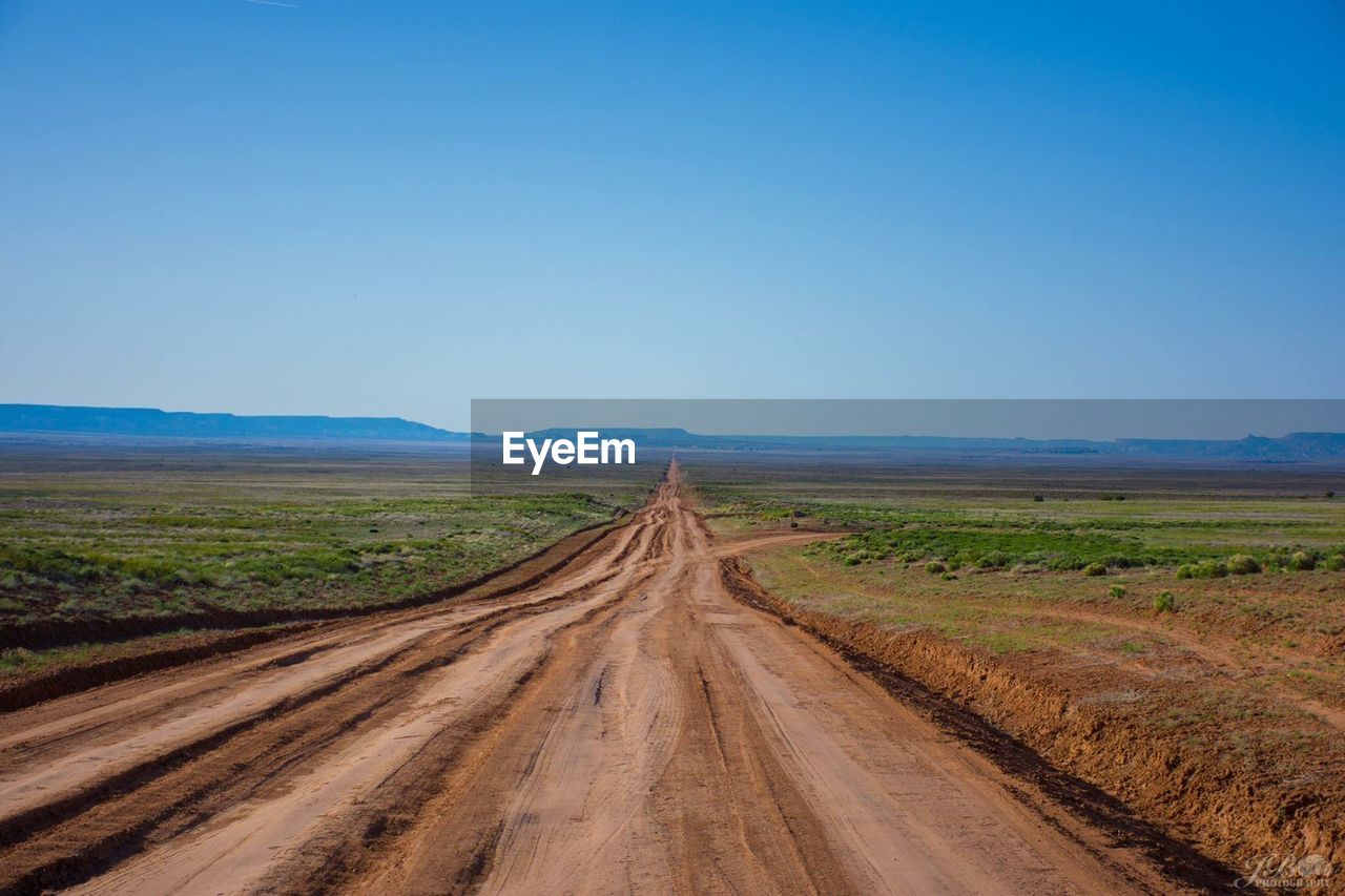 Dirt road passing through landscape against sky