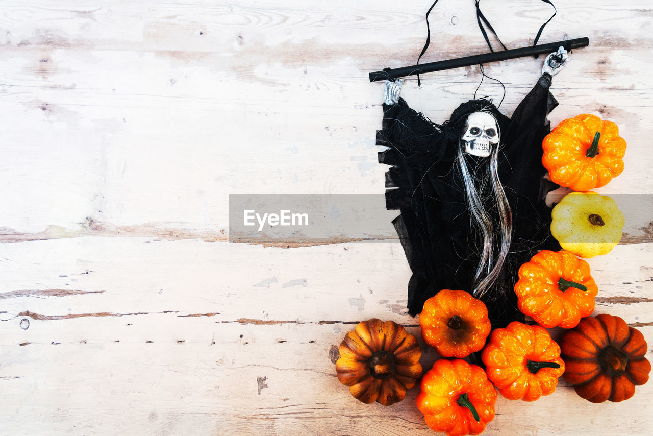 Directly above view of pumpkins and witch against wooden table