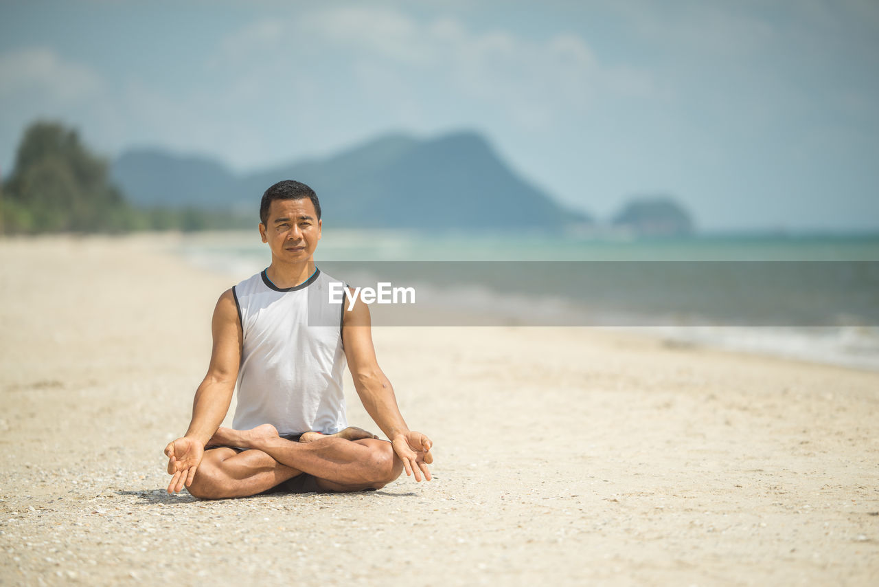 PORTRAIT OF SMILING YOUNG MAN AT BEACH