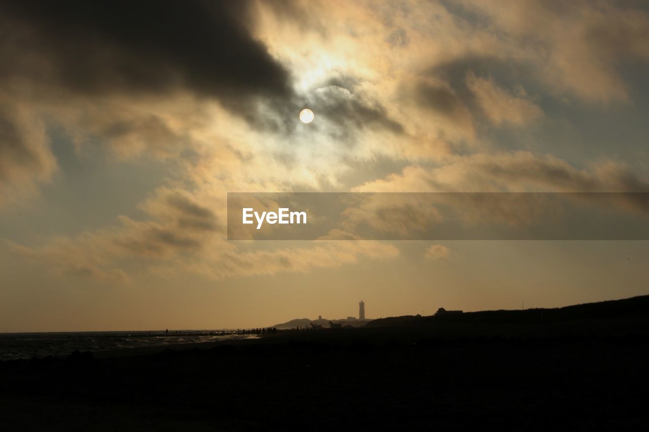 Silhouette of beach against cloudy sky