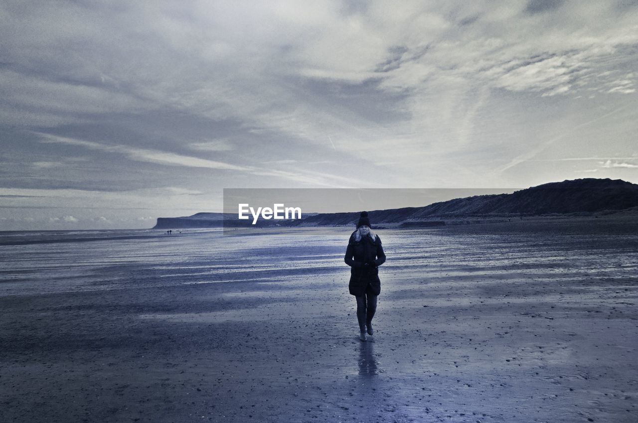 REAR VIEW OF MAN WALKING ON BEACH