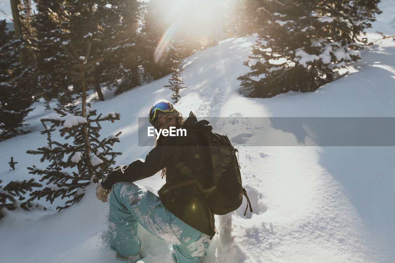 Young woman with backpack on snowy field during sunny day