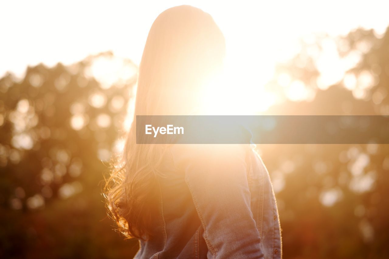 PORTRAIT OF WOMAN STANDING IN BRIGHT SUN