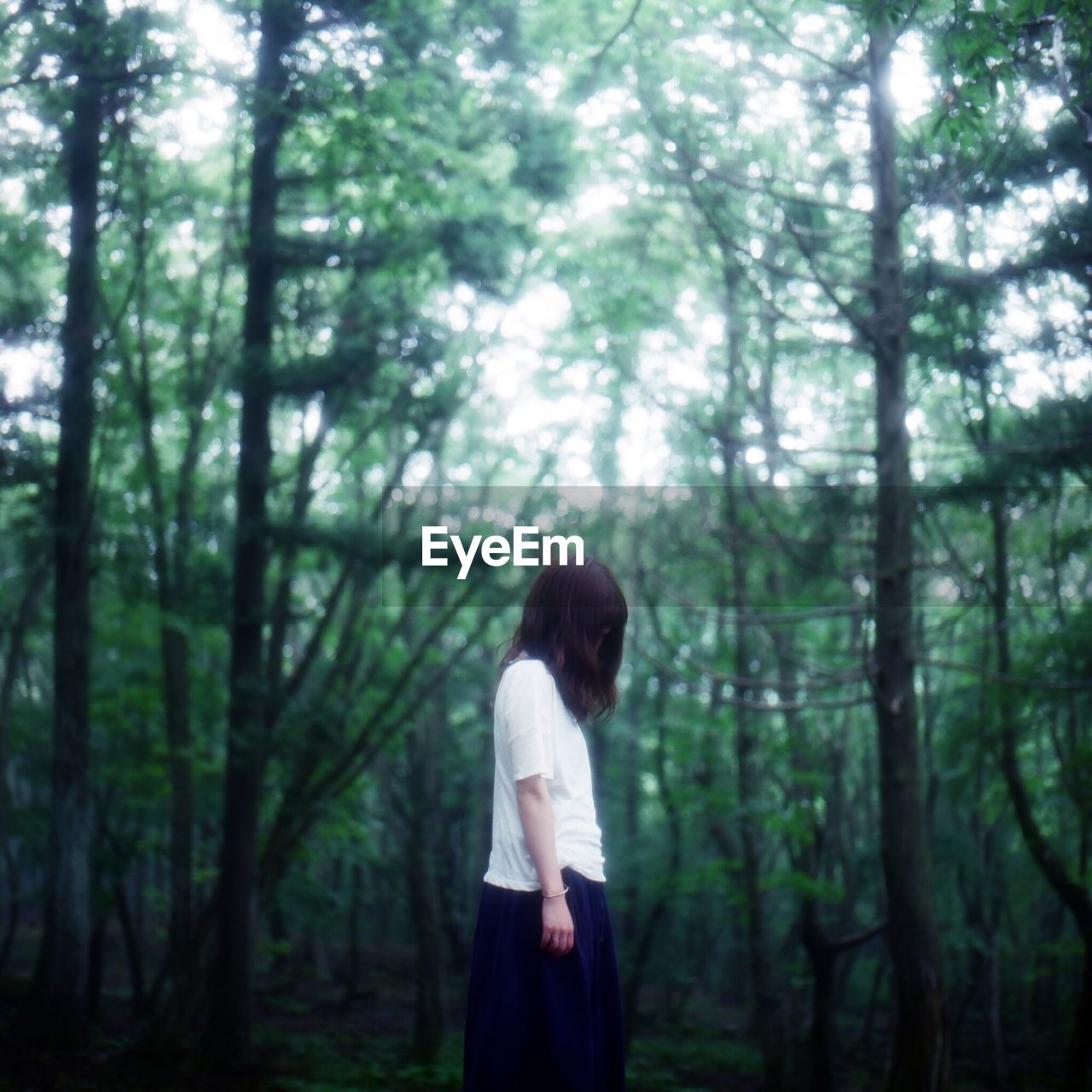 Woman with obscured face standing in forest