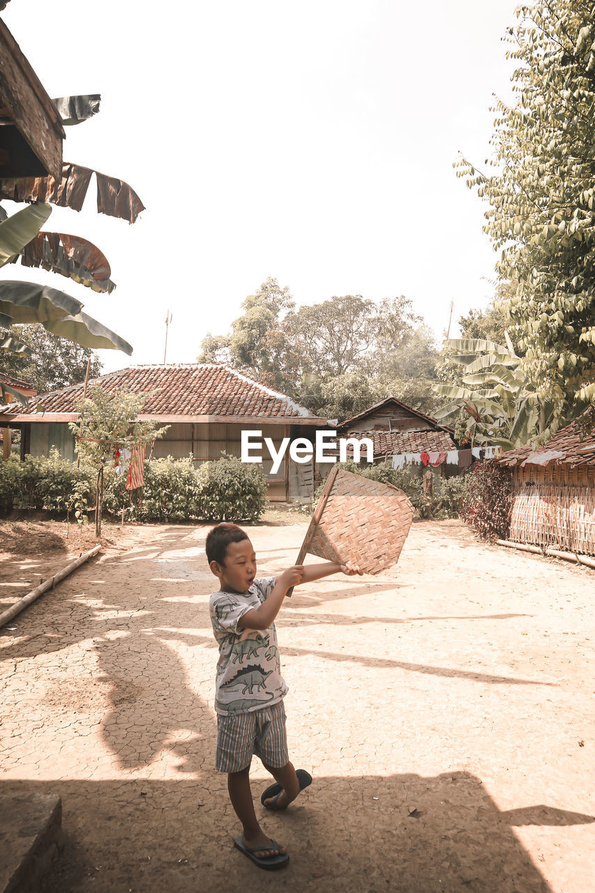 Full length of boy with arms raised against sky