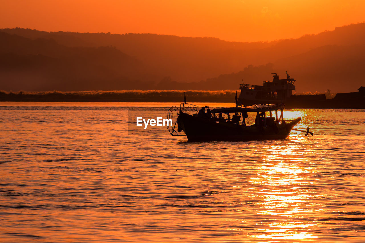 Silhouette boat in sea against sky during sunset