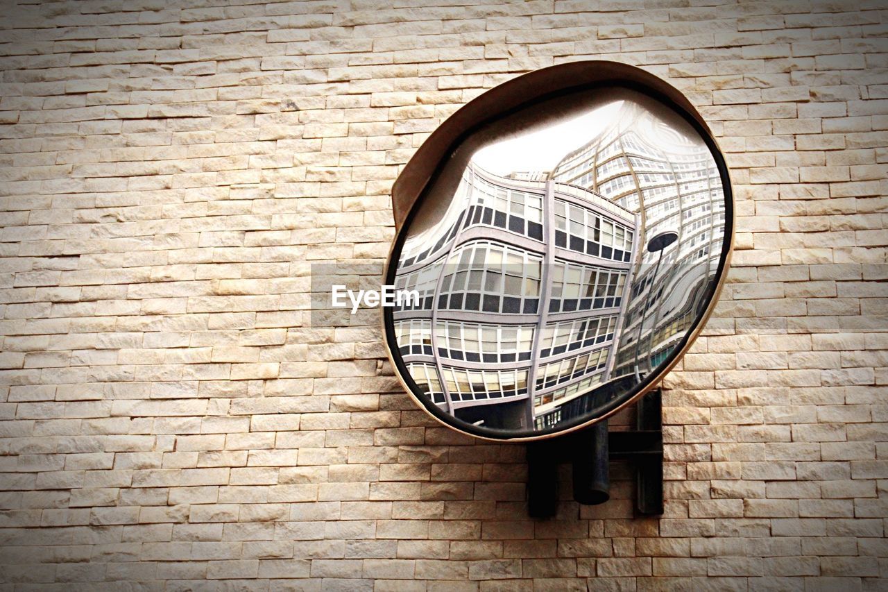 Close-up of convex mirror on textured wall