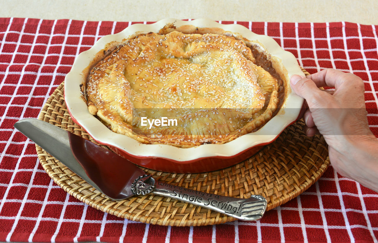 Cropped image of person holding apple pie bowl