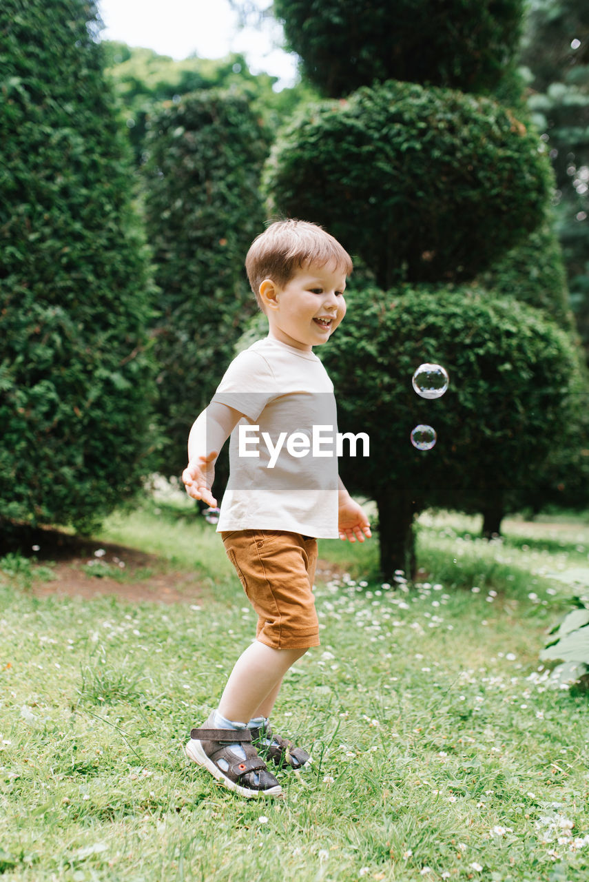 Emotional portrait of a happy and cheerful three-year-old little boy running after soap bubbles