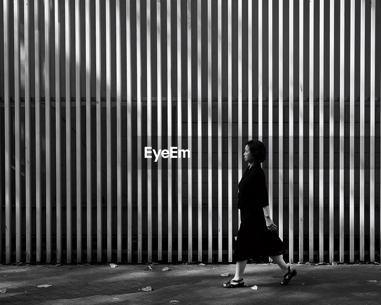 Side view of woman walking on road against wall