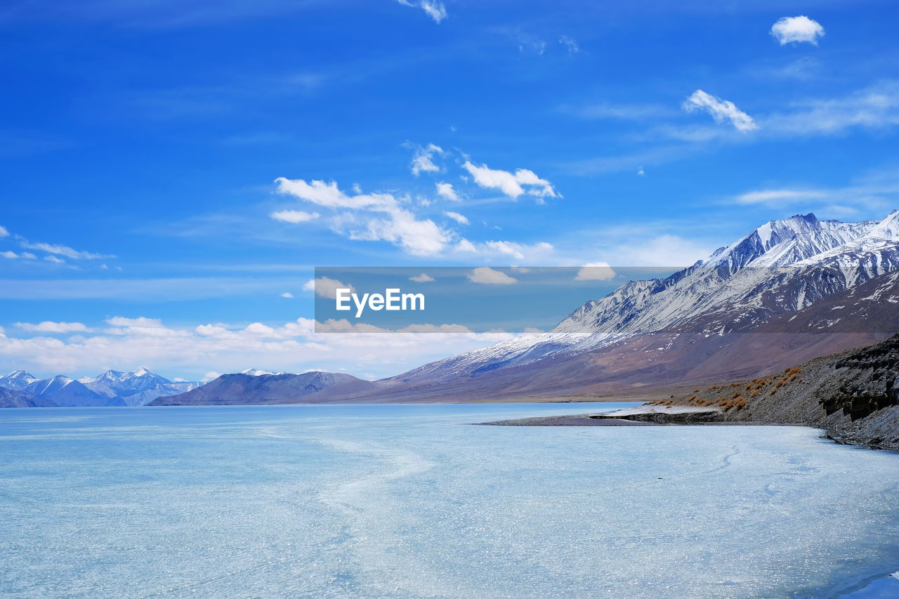 Scenic view of snowcapped mountains against blue sky